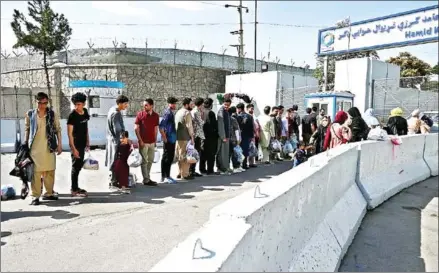  ?? AFP ?? Afghans hoping to leave Taliban-controlled Afghanista­n queue at the main entrance gate of Kabul airport.