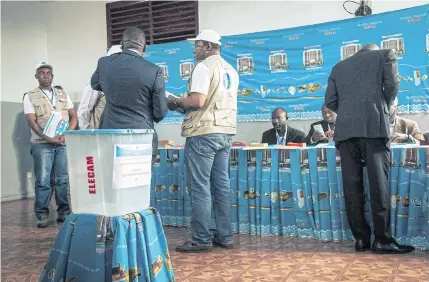  ?? AFP ?? Internatio­nal observers from ECCAS control the polling station where President Paul Biya was to vote in Yaounde yesterday.