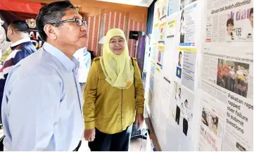  ??  ?? Ibrahim (left) reads informatio­n about Balakong’s state by-election at the media centre. — Bernama photo