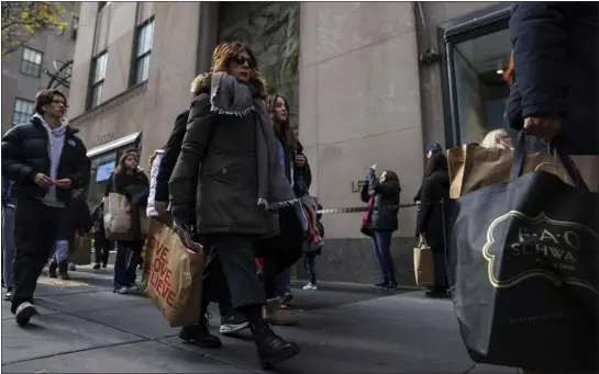  ?? JULIA NIKHINSON — THE ASSOCIATED PRESS FILE ?? Shoppers carry bags down Fifth Avenue on Nov. 25in New York.
