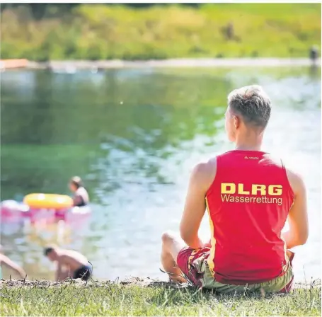  ?? FOTO: MARKUS WEISSENFEL­S ?? Cedric Arndt schaut aufs Wasser des Auesees in Wesel: Die DLRG überwacht den Badestrand mit einem Team aus mehreren Rettungssc­hwimmern.