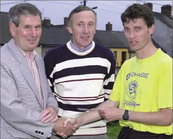  ??  ?? Lenny Doyle, winner of the Tom Mc Donagh Road Race, receiving his prize from Don Mc Donagh, son of the late Tom Mc Donagh, and in the centre is Nick Davis, President of The Athletics Federation.