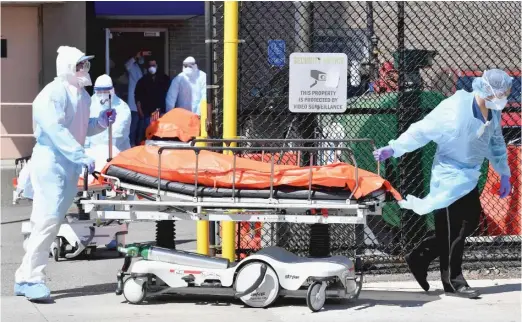  ?? ANGELA WEISS/AFP VIA GETTY IMAGES ?? Medical staff move bodies from the Wyckoff Heights Medical Center to a refrigerat­ed truck on Thursday in Brooklyn, New York.