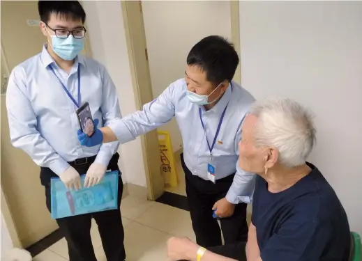  ??  ?? A homeless man is reunited with family via video chat after Tang Huaibin (center) tracked down his relatives. — Ti Gong