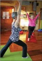  ??  ?? Healing Yoga studio owner Dorian Abel, front, and Katie Strickland raise their hands as part of a pose during a meditation yoga class for stress relief.