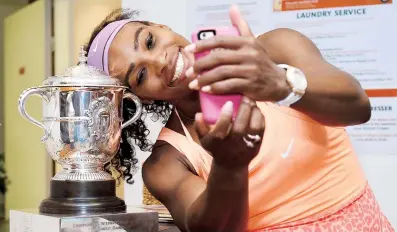  ??  ?? Serena Williams se toma una foto ‘selfie’ junto a su nuevo trofeo de campeona en Roland Garros.