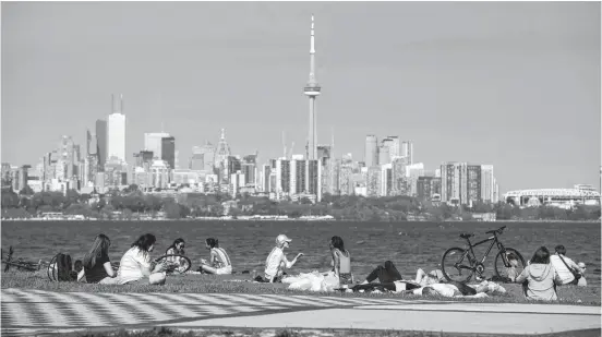  ?? REUTERS/CARLOS OSORIO ?? People maintain social distance as they sit at Humber Bay Shores park while Ontario prepares for more phased re-openings from the coronaviru­s disease restrictio­ns in Toronto.