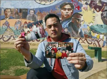  ?? REED SAXON — ASSOCIATED PRESS ?? Filipino-American Jeff DeGuia, 28, holds up family pictures at Unidad (Unity) Park in Los Angeles earlier this month.