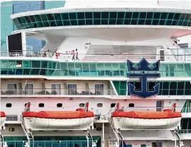  ?? CARL JUSTE cjuste@miamiheral­d.com ?? Crew members walk on the upper deck of Royal Caribbean’s Majesty of the Seas at PortMiami on May 14. Royal Caribbean Internatio­nal CEO Michael Bayley said it’s looking like there will be COVID-19 testing for passengers when cruising resumes.