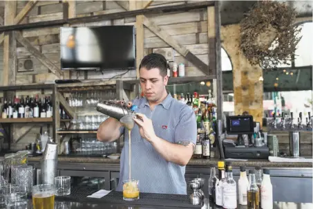  ??  ?? Sebastian Brown pours a cocktail while working at East End. Many of the lounge’s beers, cider and wines come in bottles to-go.