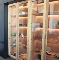  ??  ?? The apartment features a variety of lightcolou­red timbers. These glassfront­ed cabinets are at one end of the kitchen.