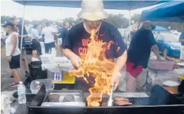  ??  ?? Scott Nuss, of Vernon, flips burgers on a grill while he tailgates with UConn football fans, family and alumni before an open practice at Pratt & Whitney Stadium at Rentschler Field on Saturday.