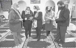  ?? MARKMIRKO/HARTFORD COURANT ?? Hafiz Naheed, left, and Ghulam Sarwar talk with their daughters Alina, Sumrina and Tehmina at a vaccine clinic in the Minhaj ul Quran Al-Noor Islamic Center in Ellington.