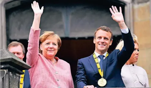  ??  ?? Kanzlerin Merkel und Frankreich­s Präsident Emmanuel Macron mit Ehefrau Brigitte am Donnerstag auf dem Balkon des Aachener Rathauses.