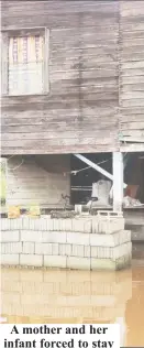  ??  ?? A mother and her infant forced to stay on the stairs of their home as a result of the flooding in Canal Number One