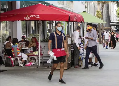  ?? PEDRO PORTAL pportal@miamiheral­d.com ?? People walking and dining on Lincoln Road in Miami Beach wear facial masks while others don’t during the weekend.