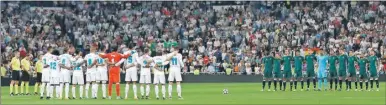  ??  ?? Los jugadores del Real Madrid y los del Betis se abrazan en el círculo central del Santiago Bernabéu, para guardar un minuto de silencio, ayer
