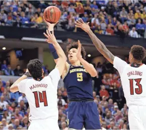  ?? TNS ?? Michigan’s D.J. Wilson shoots over Louisville’s Anas Mahmoud and Ray Spalding.