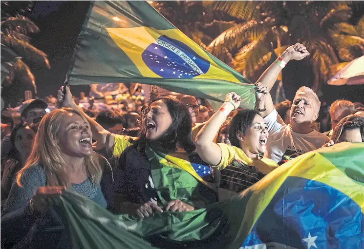  ??  ?? Los simpatizan­tes de Bolsonaro celebraron ruidosamen­te ayer en Río de Janeiro, donde vive el presidente electo