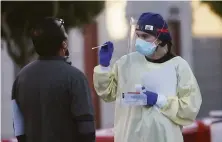  ?? Lea Suzuki / The Chronicle 2020 ?? A staffer at a coronaviru­s test site on Armstrong Avenue and Keith Street in San Francisco wields a swab in November.