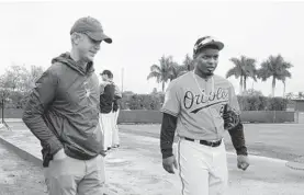  ?? LLOYD FOX/BALTIMORE SUN ?? Orioles general manager Mike Elias, left, talks with relief pitcher Mychal Givens during a spring training workout at the team’s complex in Sarasota, Fla.