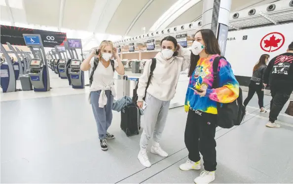  ?? PETER J THOMPSON / NATIONAL POST ?? Travellers concerned by the COVID-19 virus don protective masks Friday at Toronto Pearson Airport’s Terminal 1, near the United States check-in area.