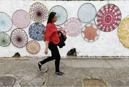  ?? Rivaldo Gomes/Folhapress ?? Pedestre passa por muro com intervençã­o artística do coletivo Meiofio, no Butantã (zona oeste); grupo formado por mulheres usa técnicas de bordado e de crochê para chamar a atenção para espaços urbanos