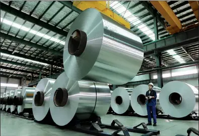  ?? AP ?? A worker arranges rolls of aluminum at a factory in China’s Anhui province. The United States plans to levy an import tax of up to 81 percent on aluminum foil from China.