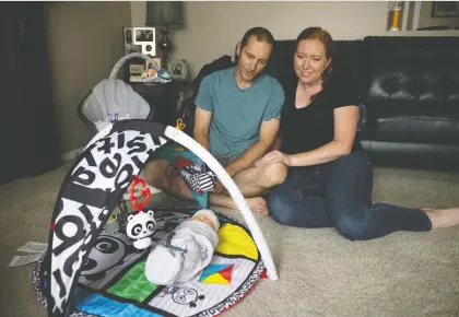  ?? TROY FLEECE / REGINA LEADER-POST ?? Marie Schultz and her husband Taylor at home with their newborn son Ciaran on Tuesday, The couple tried to have a child for seven years, pursuing treatments like IVF and egg donorship. Ciaran was born from an egg donated by Marie's cousin which was fertilized in a lab and implanted into Marie's co-worker, who acted as a surrogate. Marie also wants to raise awareness of the issues surrogate families face.