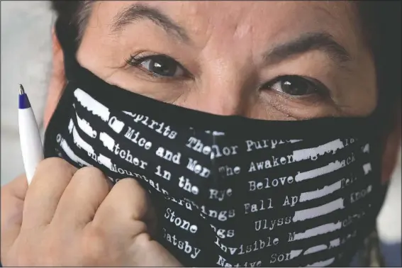  ?? (AP/Charles Krupa) ?? Poet Tammi Truax wears a protective mask at her writing table July 29 at her home in Eliot, Maine. Truax, the poet laureate for Portsmouth, N.H., pens a weekly pandemic poem that is included in the city’s covid-19 newsletter.