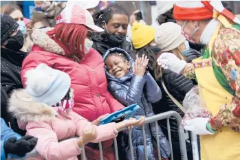  ?? ANNA WATTS/THE NEW YORK TIMES ?? Tamonai Skinner, 5, reacts after a clown tosses confetti her way Thursday during the Macy’s Thanksgivi­ng Day Parade in New York. The parade, complete with giant balloons steered down city streets, was back in full swing. With no COVID-19 vaccines and a surge in cases last Thanksgivi­ng, the parade was limited to one city block.