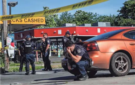  ?? MATT STONE/USA TODAY NETWORK ?? Louisville police were on guard inside police tape at the intersecti­on of 26th and Broadway on Monday after a man was shot and killed by police and National Guard personnel outside Dino’s Market.