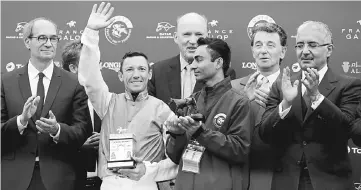  ??  ?? Frankie Dettori (second left), flanked by head of French Parliament Finance Commission Eric Woerth (left), reacts as he celebrates on the podium during the price ceremony after winning the 96th Qatar Prix de l’Arc de Triomphe horse race at the...