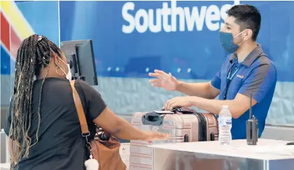  ?? TONY GUTIERREZ/AP ?? Southwest Airlines employee Oscar Gonzalez assists a passenger at the ticket counter at Love Field in Dallas.