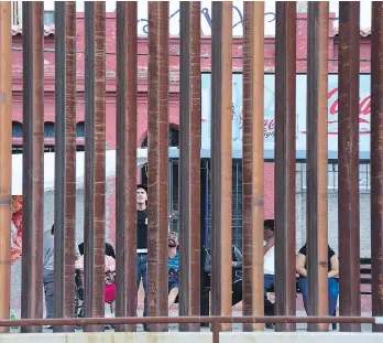  ?? FREDERIC J. BROWNFREDE­RIC J. BROWN/AFP/ GETTY IMAGES ?? People wait at a bus stop in Nogales, in the state of Sonora, Mexico, as seen through a U.S.-Mexico border fence.