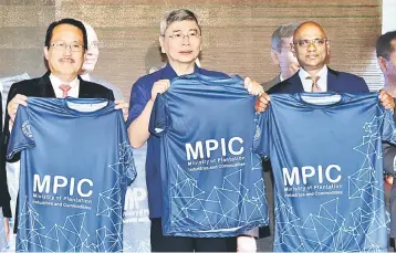  ??  ?? Mah (middle) showcases a ministry shirt during the ministry’s monthly gathering yesterday. Also present is deputy minister Datuk Datu Nasrun Datu Mansur (left) and Ministry Secretary General Datuk K. Yogeesvara­n. — Bernama photo