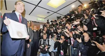  ??  ?? Still in the running: Tang holding up papers confirming his candidacy for next month’s election at the Hong Kong Registrati­on and Electoral Office yesterday. — AFP