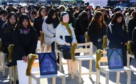  ?? JUNG YEON-JE/AFP/GETTY IMAGES ?? Women sit in silent support Wednesday with a statue of “comfort woman” commemorat­ing the death of eight wartime sex slaves this year in Seoul.