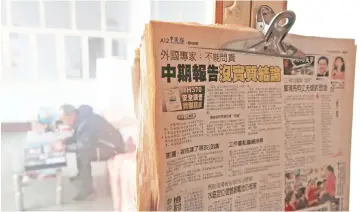  ??  ?? Newspapers with articles on the missing MH370 hang by a window as Li looks at a photo album during a Reuters interview at his house. — Reuters photos