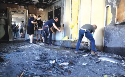  ?? (Marc Israel Sellem/The Jerusaelm Post) ?? VOLUNTEERS CLEAN a school in Lod yesterday, the morning after it was burned during riots.