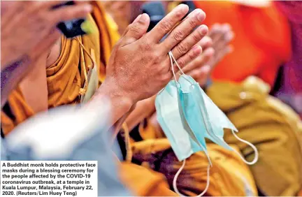  ??  ?? A Buddhist monk holds protective face masks during a blessing ceremony for the people affected by the COVID-19 coronaviru­s outbreak, at a temple in Kuala Lumpur, Malaysia, February 22, 2020. (Reuters/Lim Huey Teng)