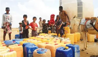  ?? File/AFP ?? Yemeni children stand near water containers at a distributi­on point in a camp for displaced people in the Abs district of the country’s northweste­rn Hajjah province. The war in Yemen has displaced hundreds of thousands of people.