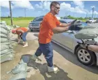  ??  ?? St. Bernard Parish Sheriff’s Office inmate workers move sandbags for residents in Chalmette, La., on Thursday.