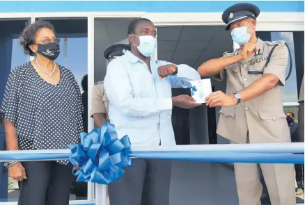  ?? CONTRIBUTE­D PHOTOS ?? Minister of Transport Robert Montague (centre) hands over the keys to a new police station at the Ian Fleming Internatio­nal Airport to Deputy Commission­er of Police Clifton Blake as Fay Hutchinson, Airports Authority of Jamaica chairman, looks on.