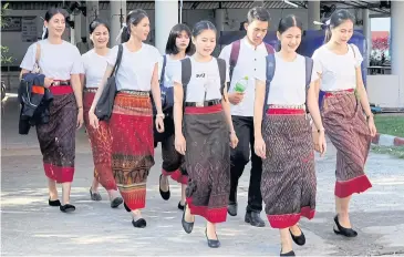  ?? PHITSANU THEPTHONG ?? University students are seen wearing ‘phasin’ as they walk to their classes. Many students have taken to experiment­ing with phasin as a uniform, which is gaining popularity in universiti­es in the lower Northeast.