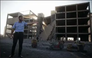  ?? AP/KHALIL HAMRA ?? A Palestinia­n policeman stands guard next to a building destroyed Saturday by an Israeli airstrike in Gaza City.