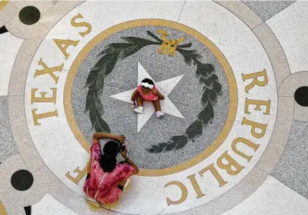  ?? Eric Gay / Associated Press ?? Michaela Herrera takes photos of her 8-month-old daughter, Jayzaiyah Lane, at the Texas Capitol. Republican­s in the Texas House voted on Tuesday to limit how racism and the history of American slavery is taught in Texas classrooms.