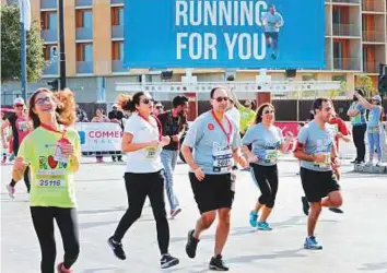  ?? AFP ?? Participan­ts run past a billboard bearing a portrait of Lebanon’s former prime minister Sa’ad Hariri during Beirut’s annual marathon yesterday.