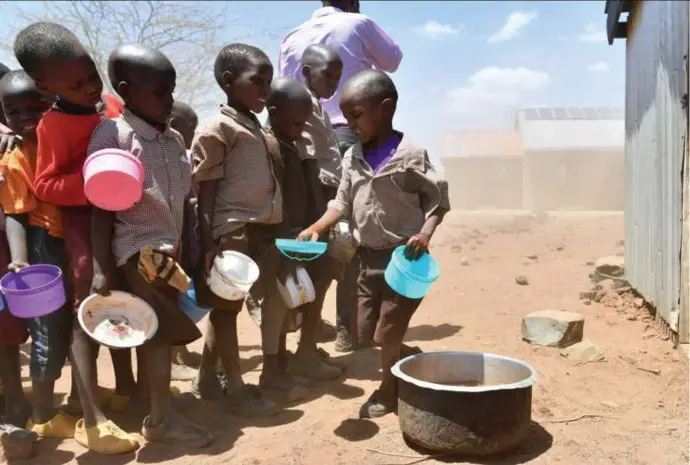  ?? © belga ?? De droogte treft ook deze Keniaanse schoolkind­eren, die hun schotels afwassen na een karige maaltijd.