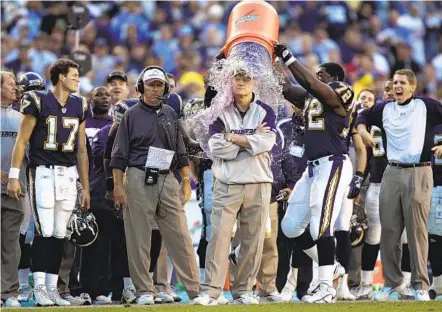  ?? K.C. ALFRED U-T ?? Philip Rivers (17) looks on as coach Marty Schottenhe­imer is dunked with water by Roman Oben (72) after his 200th NFL win in 2006.